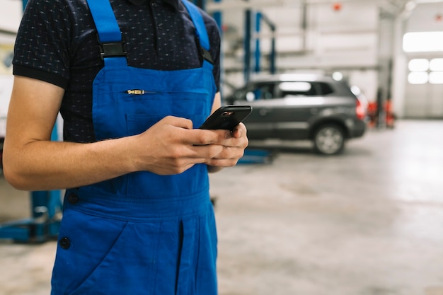 Foto grátis técnico usando telefone na oficina de carro