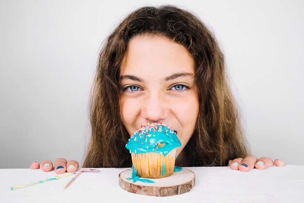 Teenage biting cupcake e olhando a câmera