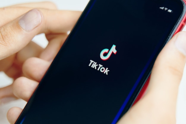 Telefone na mão. ícone do aplicativo tik tok no telefone. fechar-se.