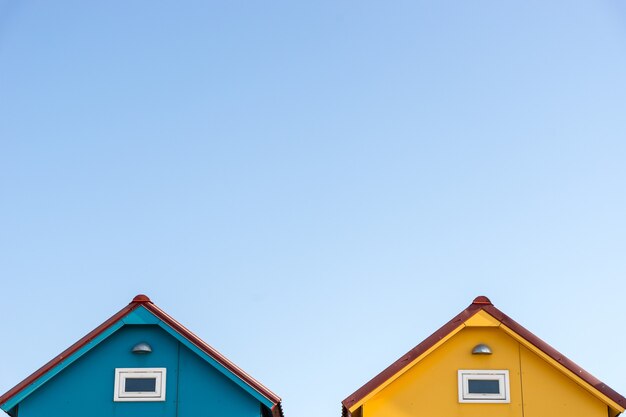 Telhados de pequenas casas azuis e amarelas com copyspace no céu
