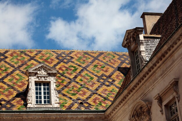 Telhas de telhado cerâmicas tradicionais em uma construção do governo em Dijon, Borgonha, França.