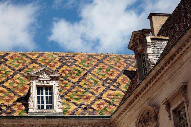 Telhas de telhado cerâmicas tradicionais em uma construção do governo em Dijon, Borgonha, França.