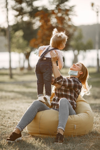 Foto grátis tema coronavirus. família em um parque de verão. mulher com uma camisa de cela.