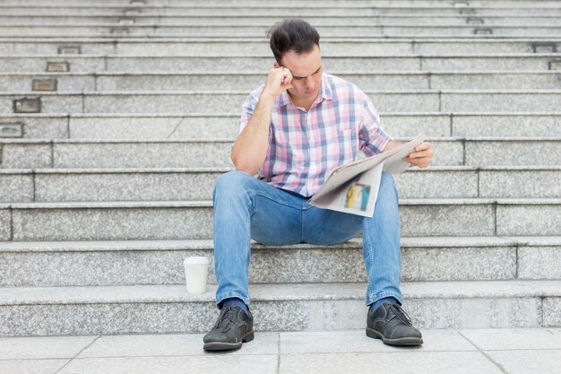 Tensed Man Reading Newspaper on City Stairway