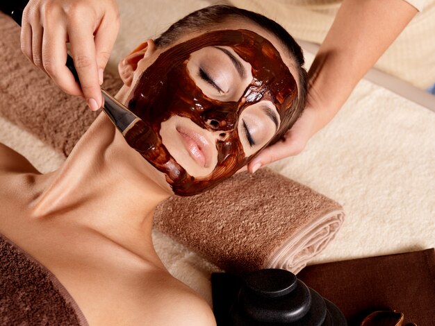 Terapia de spa para jovem recebendo máscara facial em salão de beleza - dentro de casa