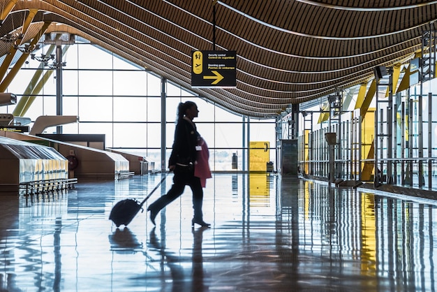 Terminal do aeroporto com pessoas movendo silhuetas e raios de sol