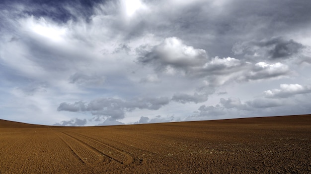 Terra de areia marrom sob o céu escuro e cinza nublado