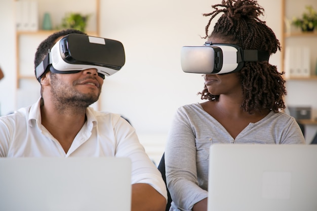 Testadores afro-americanos animados usando óculos de realidade virtual no escritório