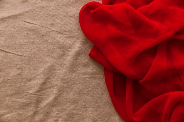 Têxtil vermelho liso no fundo da tela marrom