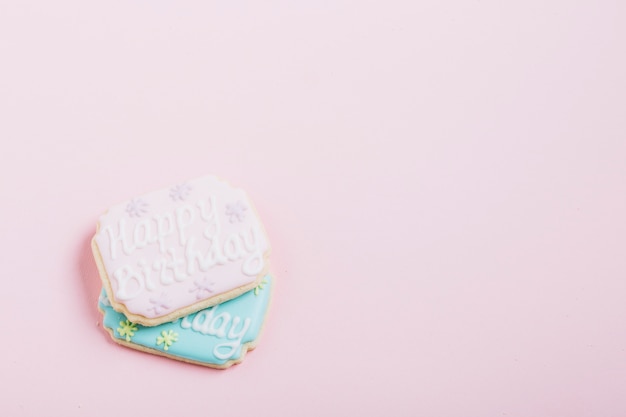 Texto de feliz aniversário em biscoitos frescos sobre fundo rosa