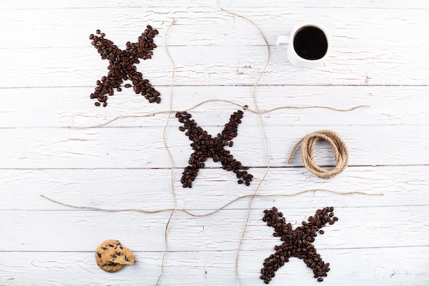 Tick-tack-toe com grãos de café, xícara, biscoitos, canela,