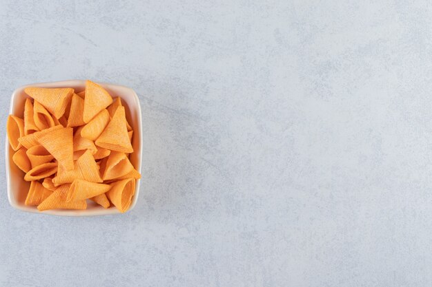 Tigela bege de triângulo em forma de chips crocantes no fundo de pedra.