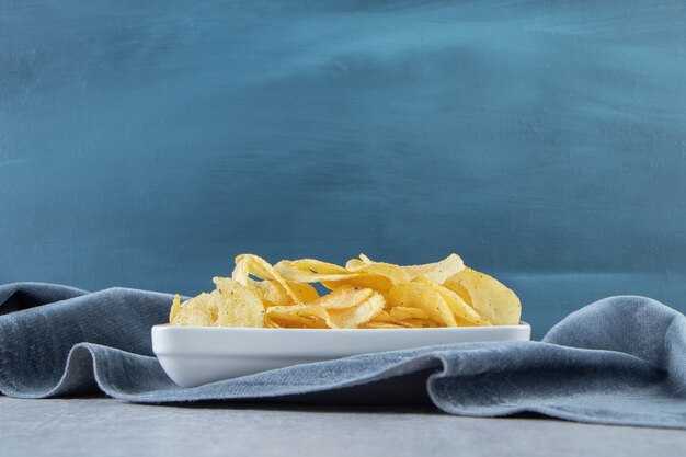 Tigela branca de batatas fritas salgadas na pedra.