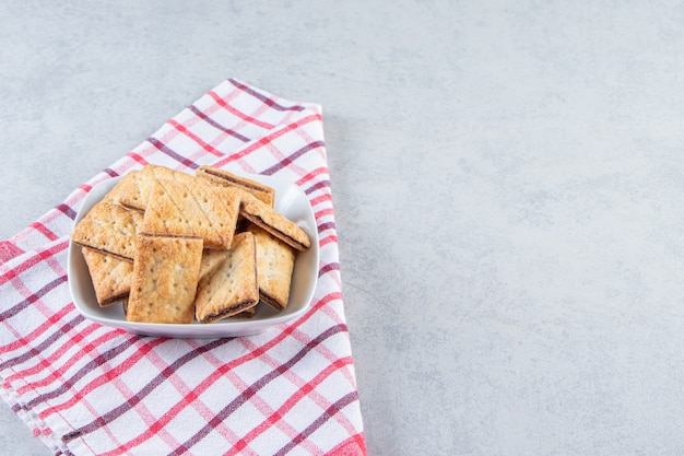 Tigela branca de saborosos biscoitos crocantes na pedra.