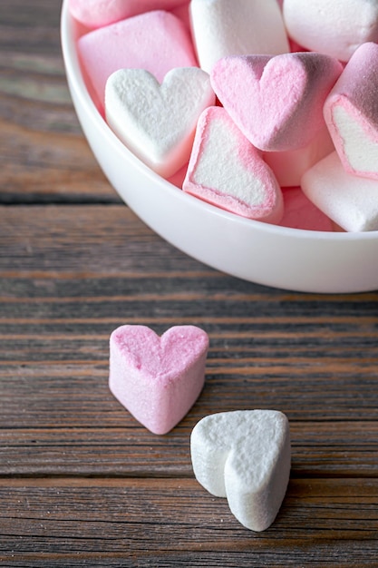 Foto grátis tigela com marshmallows em forma de corações closeup em um fundo de madeira