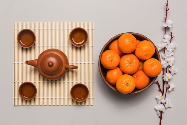 Foto grátis tigela com tangerinas perto de conjunto de chá