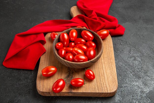 Tigela com vista inferior com tomate cereja e toalha vermelha em uma tábua de cortar em fundo escuro