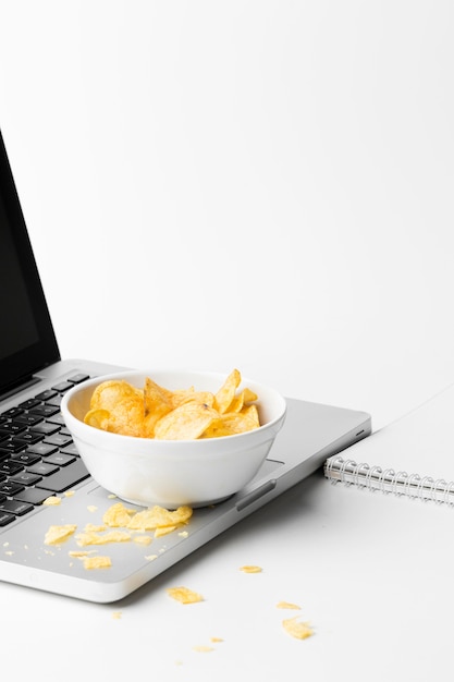 Foto grátis tigela de alto ângulo com chips no laptop