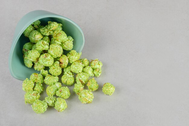 Tigela de aperitivo caiu, derramando pipoca verde cristalizada na mesa de mármore.