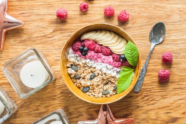 Tigela de aveia saudável com banana e frutas frescas na mesa de madeira