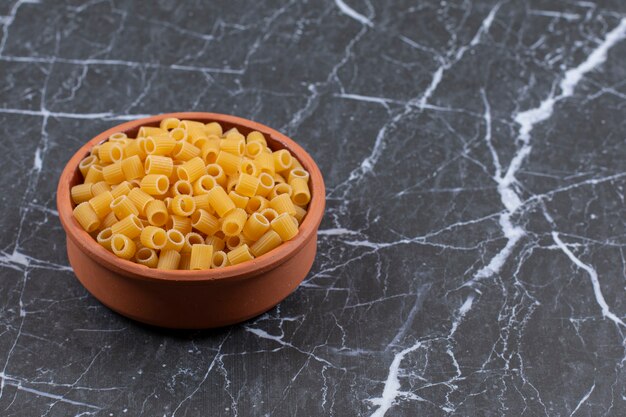 Tigela de cerâmica cheia de macarrão penne cru.