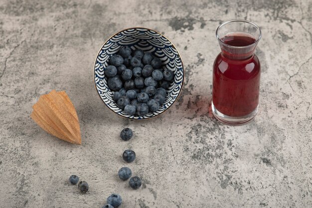 Tigela de cerâmica com deliciosos mirtilos frescos e um copo de suco