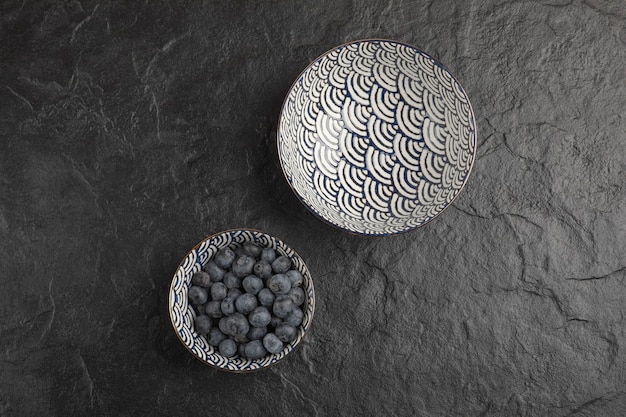 Tigela de cerâmica com deliciosos mirtilos frescos na superfície preta