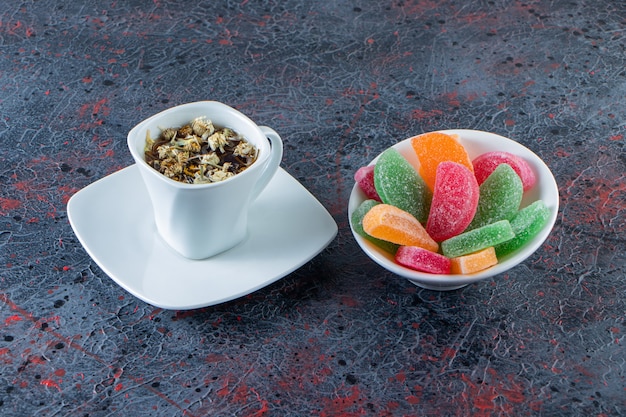 Tigela de geléias coloridas com uma xícara de chá quente na superfície escura. Foto Premium
