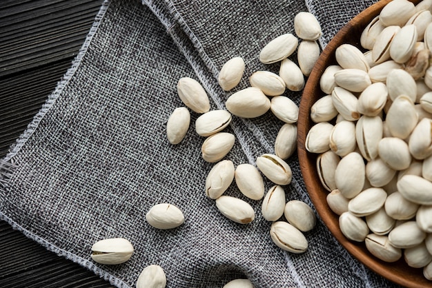 Tigela de madeira com pistache de nozes. sobre um fundo de madeira, perto de um saco de estopa. Alimentação saudável e lanche, comida vegetariana orgânica.