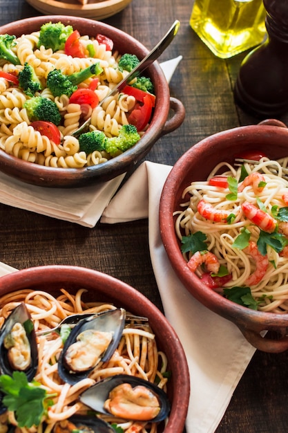 Tigela de massa vegetariana e não vegetariana na mesa de madeira