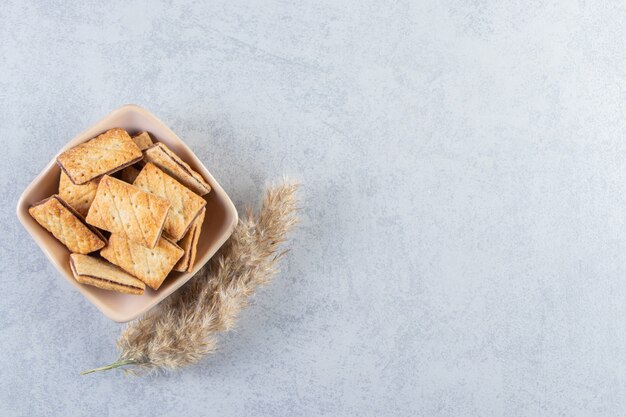 Tigela de saborosos biscoitos recheados com chocolate no fundo de pedra.