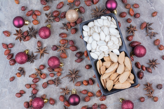 Tigela de sementes de pistache e abóbora com roseiras e bolas de Natal.