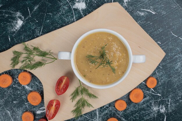Tigela de sopa de lentilha com rodelas de cenoura e tomate na placa de madeira. foto de alta qualidade