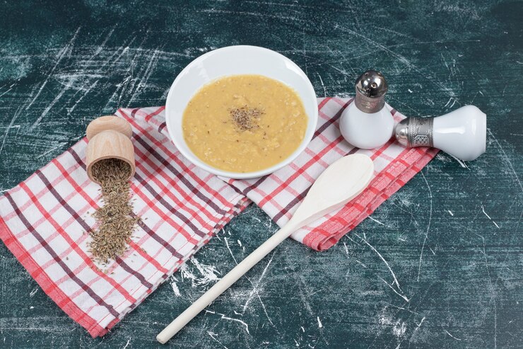 Foto grátis tigela de sopa de lentilha, sal, especiarias e toalha de mesa em fundo de mármore. foto de alta qualidade