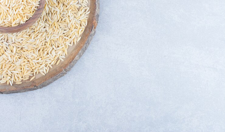 Foto grátis tigela em uma placa de madeira, cheia e cercada com uma pilha de arroz integral na superfície de mármore