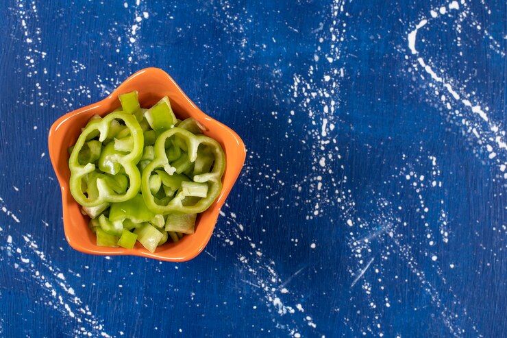 Foto grátis tigela laranja de anéis de pimentão verde fresco na superfície de mármore