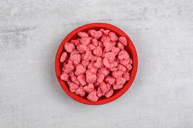 Foto grátis tigela vermelha cheia de cereais rosa na mesa de pedra.