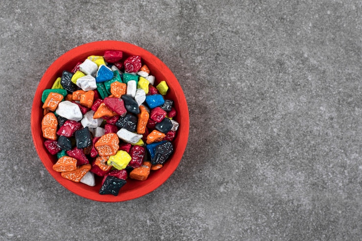 Foto grátis tigela vermelha de doces de pedra coloridos na pedra.