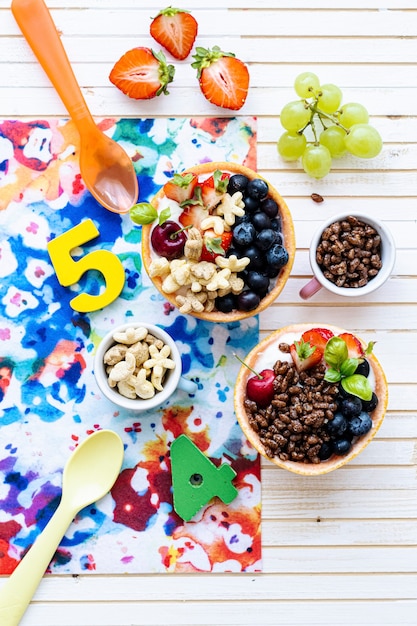 Tigelas de café da manhã para aniversário de crianças com cereais e frutas vermelhas