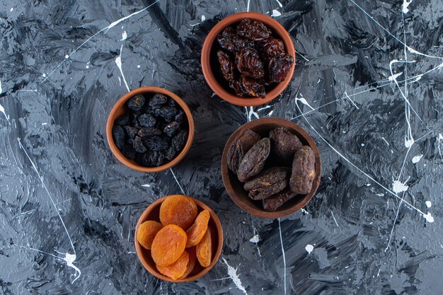 Tigelas de cerâmica com saborosas frutas secas na superfície de mármore.