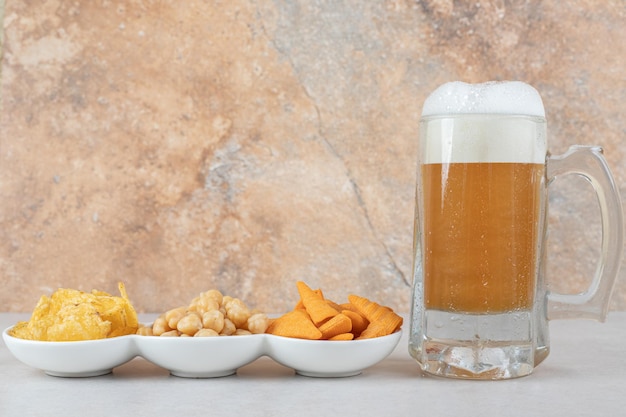 Tigelas de lanche e copo de cerveja na mesa de pedra.