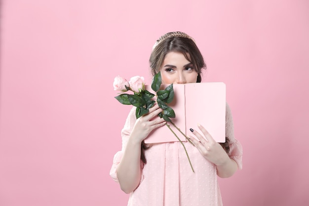 Tímida mulher segurando rosas e esconder o rosto atrás de livro
