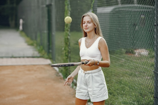 Ótimo dia para jogar! Jovem alegre em t-shirt. Mulher segurando a bola e a raquete de tênis.