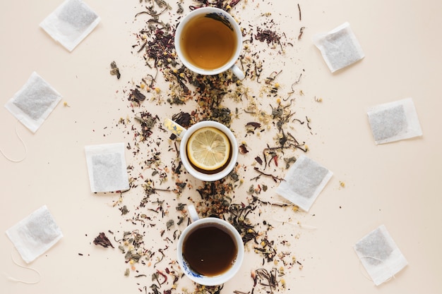 Tipo diferente de chá dispostos em uma fileira com saquinho de chá e ervas sobre o fundo colorido