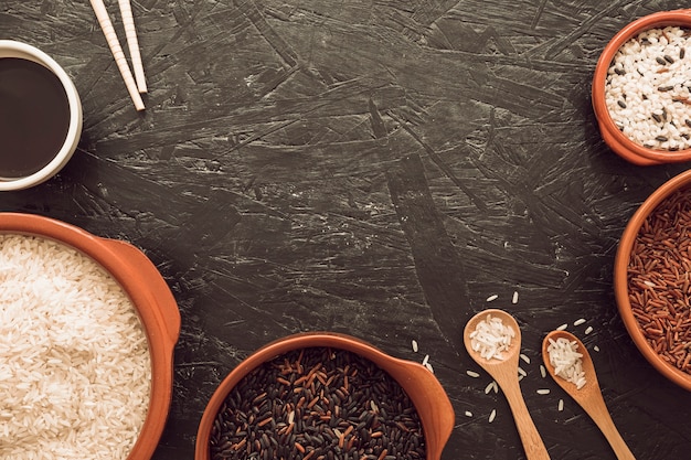 Tipo diferente de grãos de arroz tigela com molho de soja; pauzinhos e colher de pau