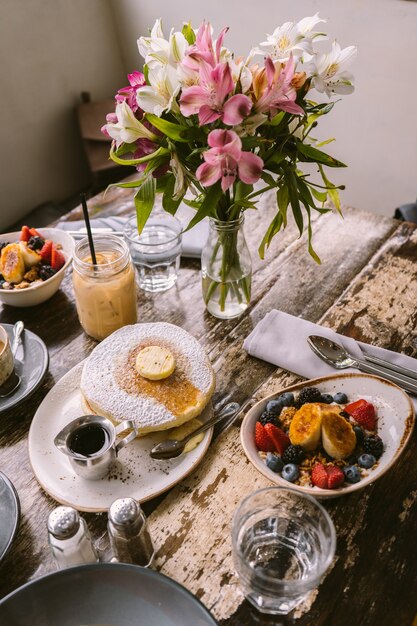 Tipos de alimentos, biscoitos e bebidas colocados na mesa em frente ao vaso de flores