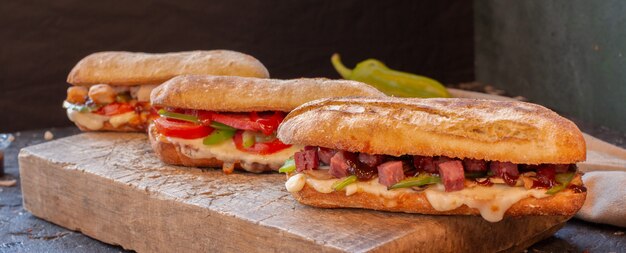 Tipos de sanduíche misto com vários alimentos em uma placa de madeira