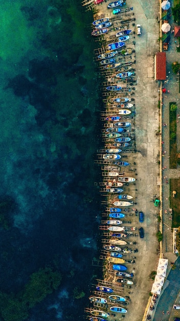 Tiro aéreo vertical de diferentes barcos estacionados na beira da costa perto da água