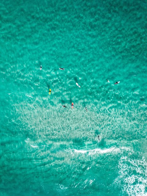 Tiro aéreo vertical surfistas com pranchas de surf em um mar azul claro