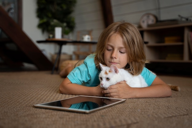 Tiro completo de criança e gato com tablet